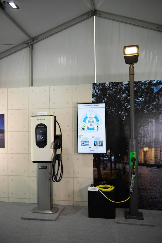 左）はホンダの外部充装置で、右）は街灯に流れる電気でも充電ができるという取り組み