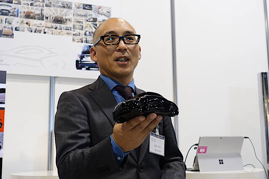 デザインの取りまとめの中島氏。手にもっているのがイメージの「黒マメ」だ